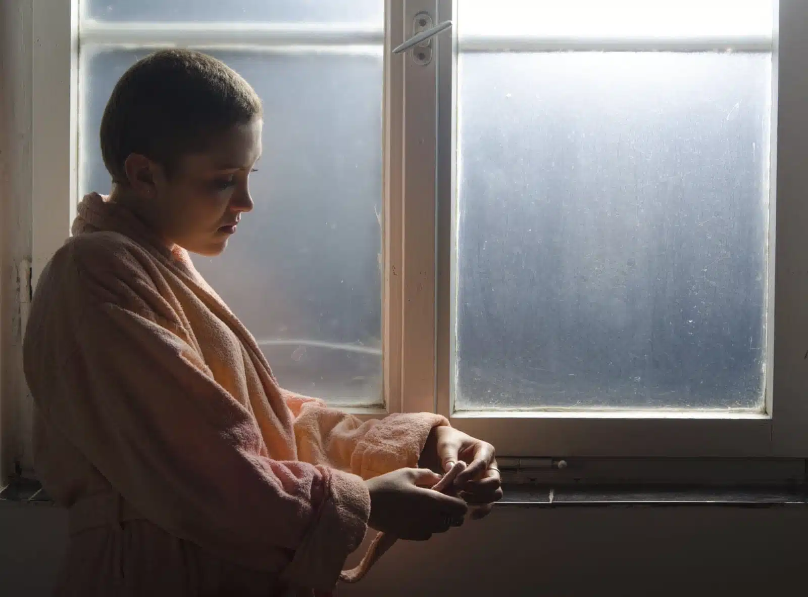 Distressed hospital patient standing near window