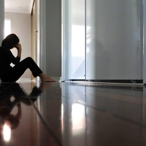 A woman sitting on the floor feeling depressed.