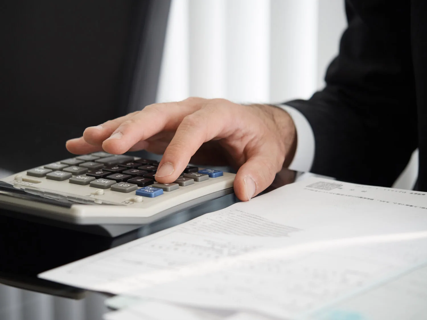 View of a lawyer’s hand using a calculator next to accident-related documents.