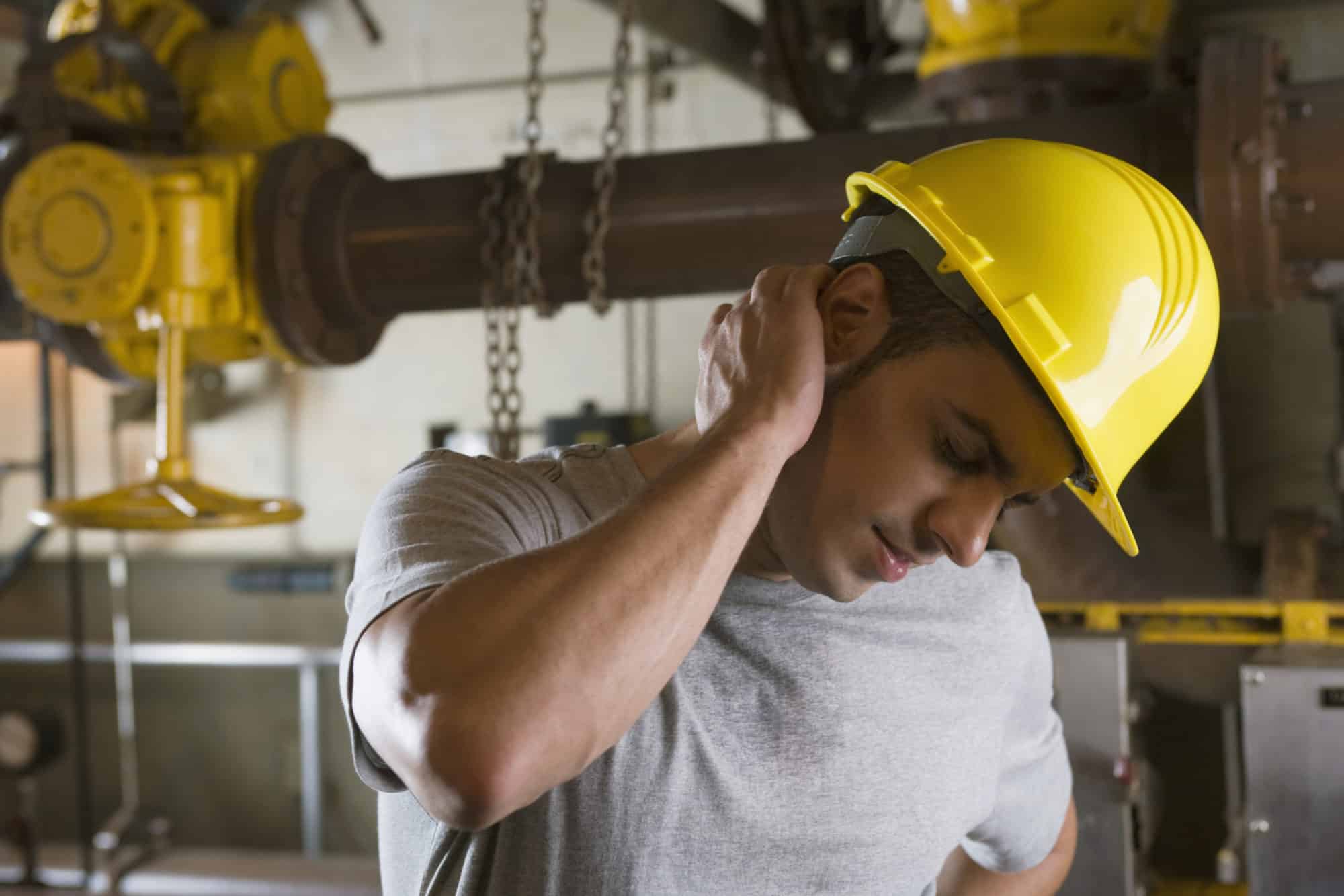 Worker wearing hardhat and experiencing neck pain