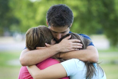 A father consoles two grieving children.
