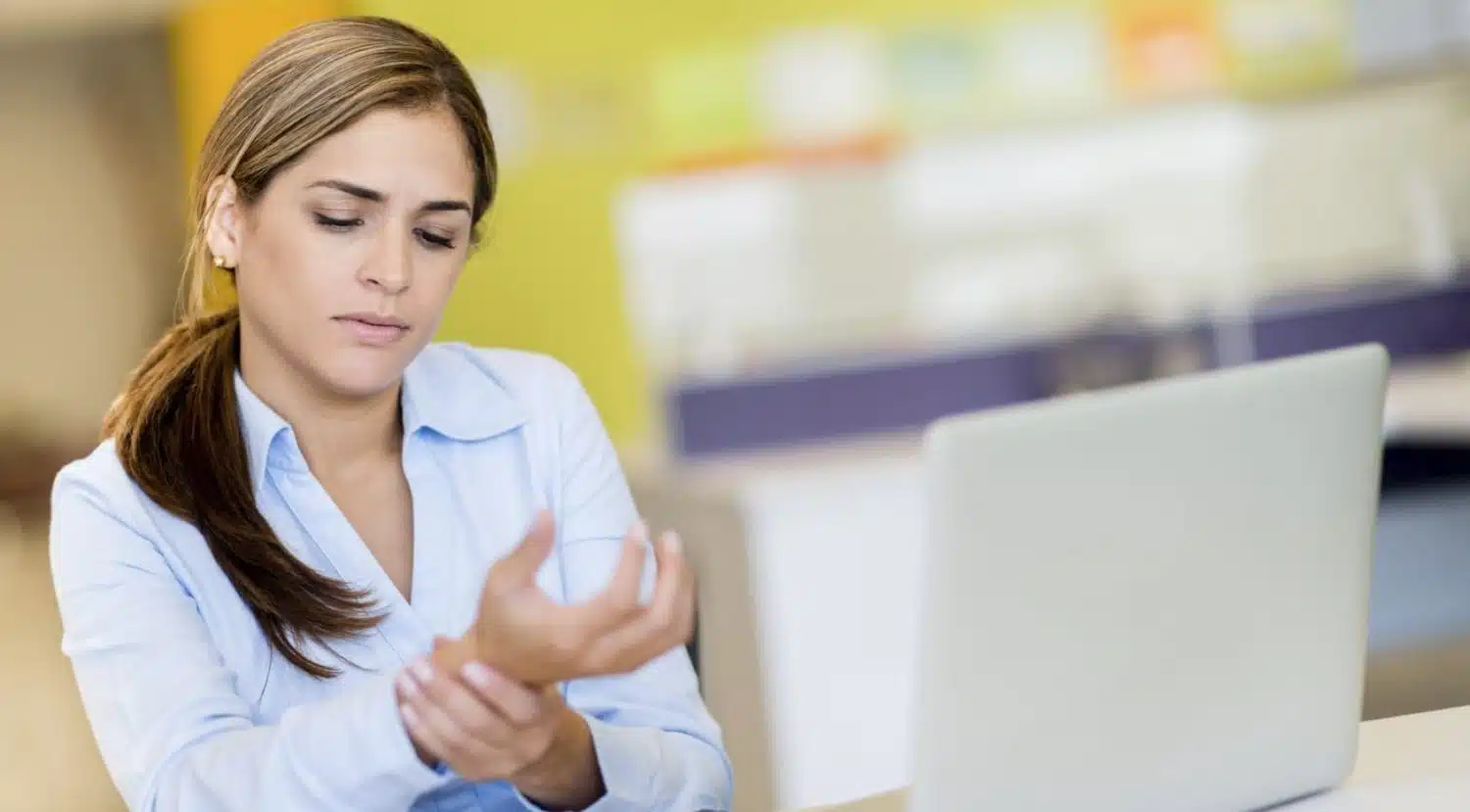 A woman holding her wrist as if in pain.