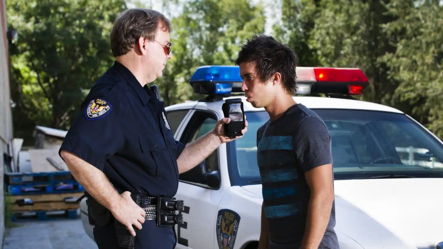 A police officer administers a breathalyzer test to an intoxicated driver at the scene of an accident.