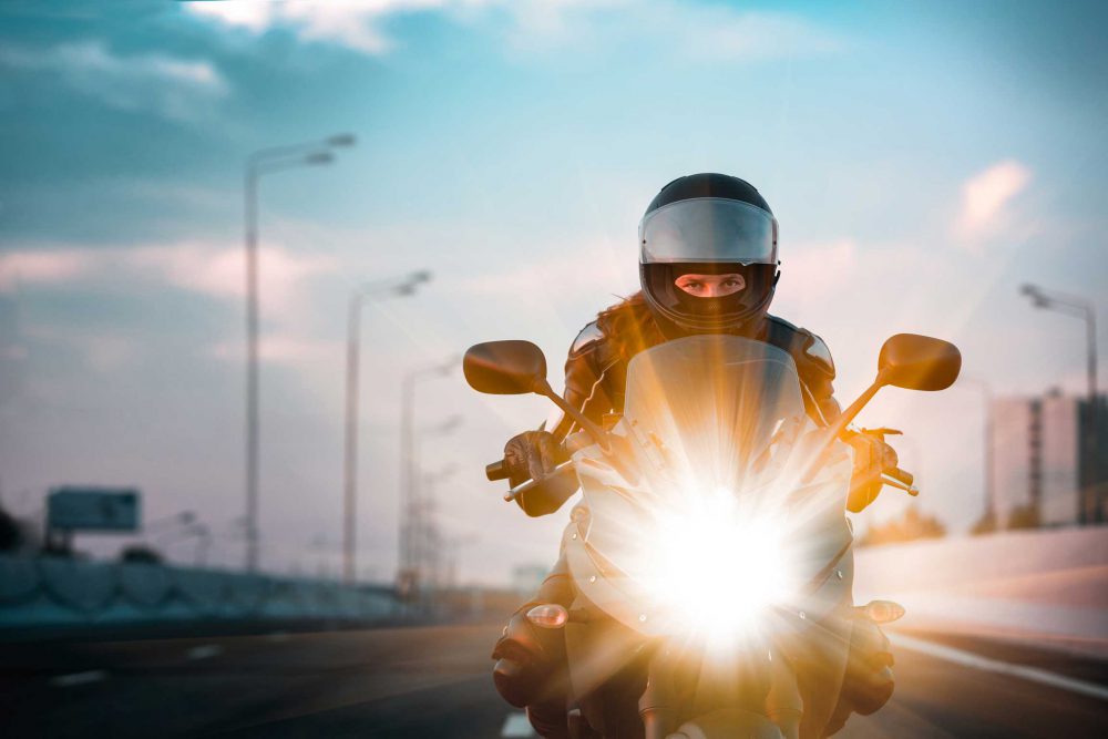 A woman riding a motorcycle down the interstate in full gear.