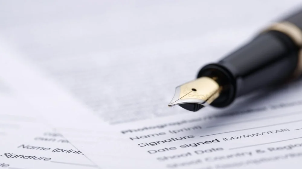 a fountain pen on a stack of contract forms