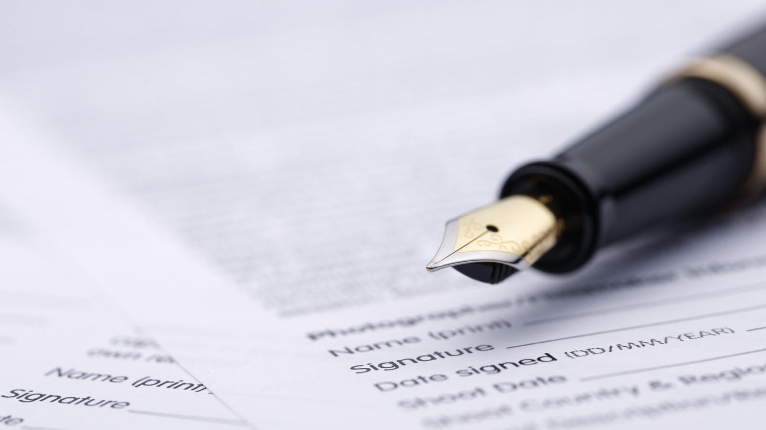 a fountain pen on a stack of contract forms