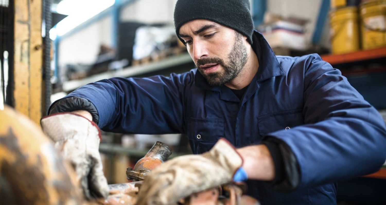 A mechanic working with a piece of machinery in a workshop.