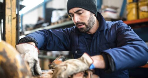 A mechanic working with a piece of machinery in a workshop.