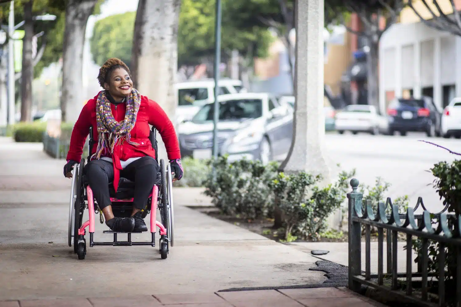 A woman rolling her wheelchair down the sidewalk in Boston