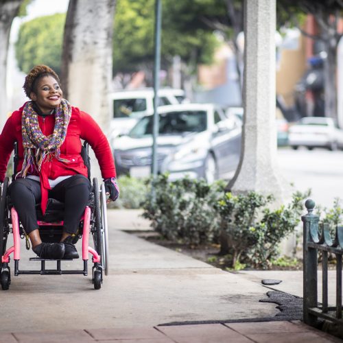 A woman rolling her wheelchair down the sidewalk in Boston