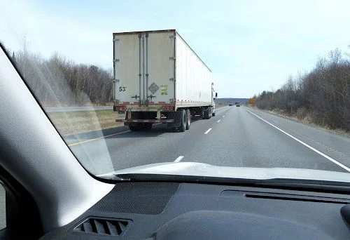 A driver is practicing driving safely near a big truck in Massachusetts by keeping their distance.