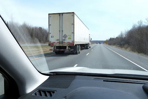 A driver is practicing driving safely near a big truck in Massachusetts by keeping their distance.
