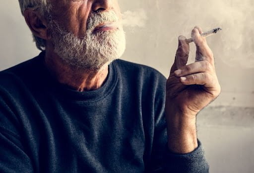 An older man smoking a cigarette.