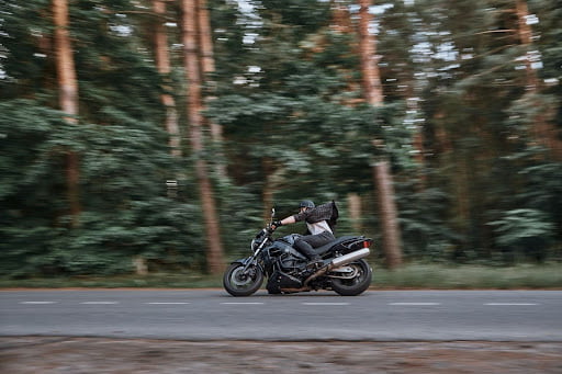 A man on a black motorcycle is speeding down the road.
