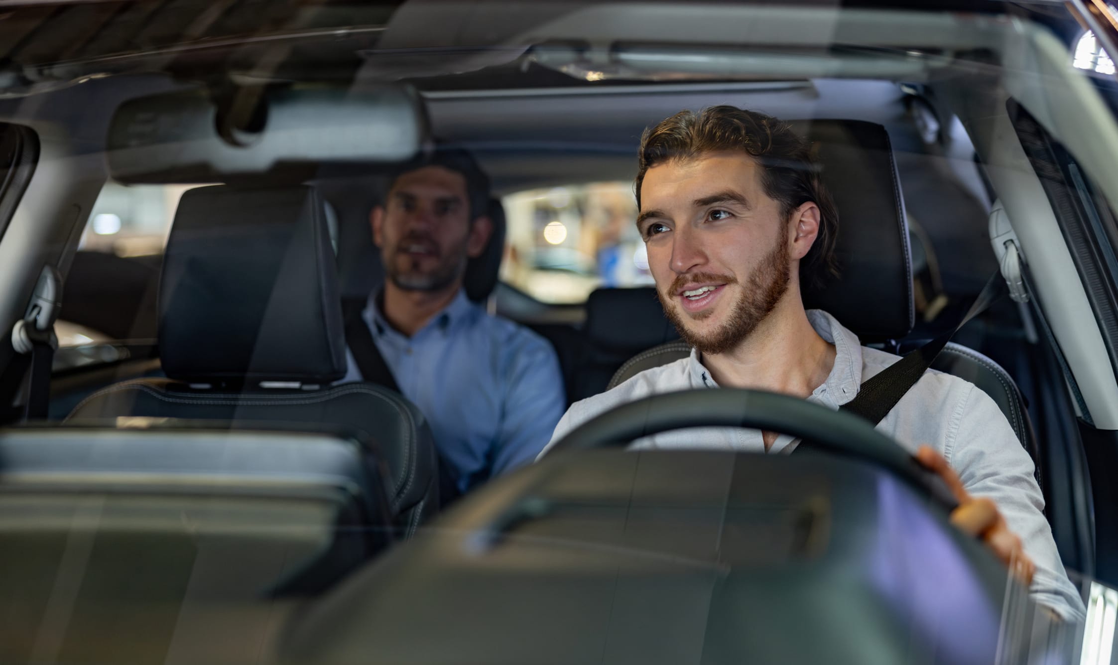 A rideshare driver looks at their rearview mirror to talk to their passenger in the backseat.