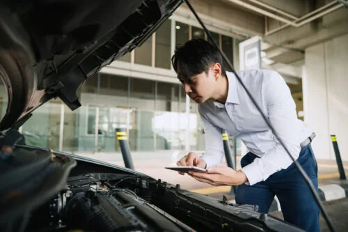 An insurance adjuster reviews the damage to a vehicle, under the hood.
