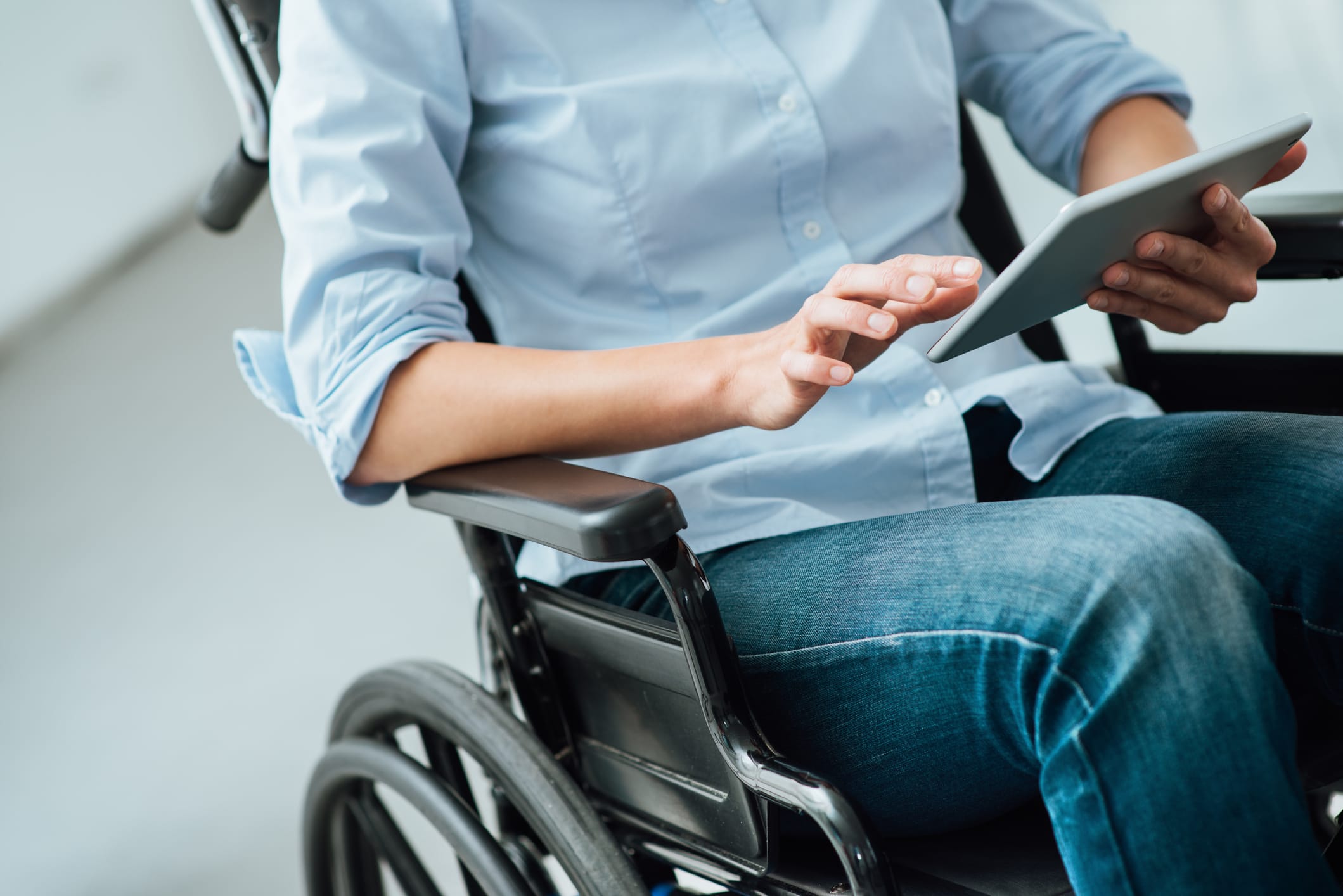 A person in a wheelchair using a tablet to apply for disability benefits.