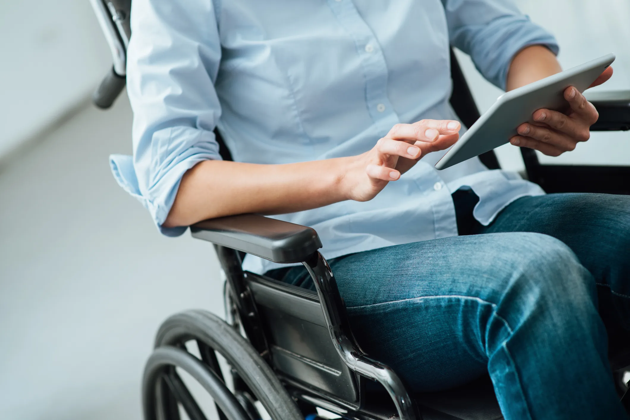 A person in a wheelchair using a tablet to apply for disability benefits.