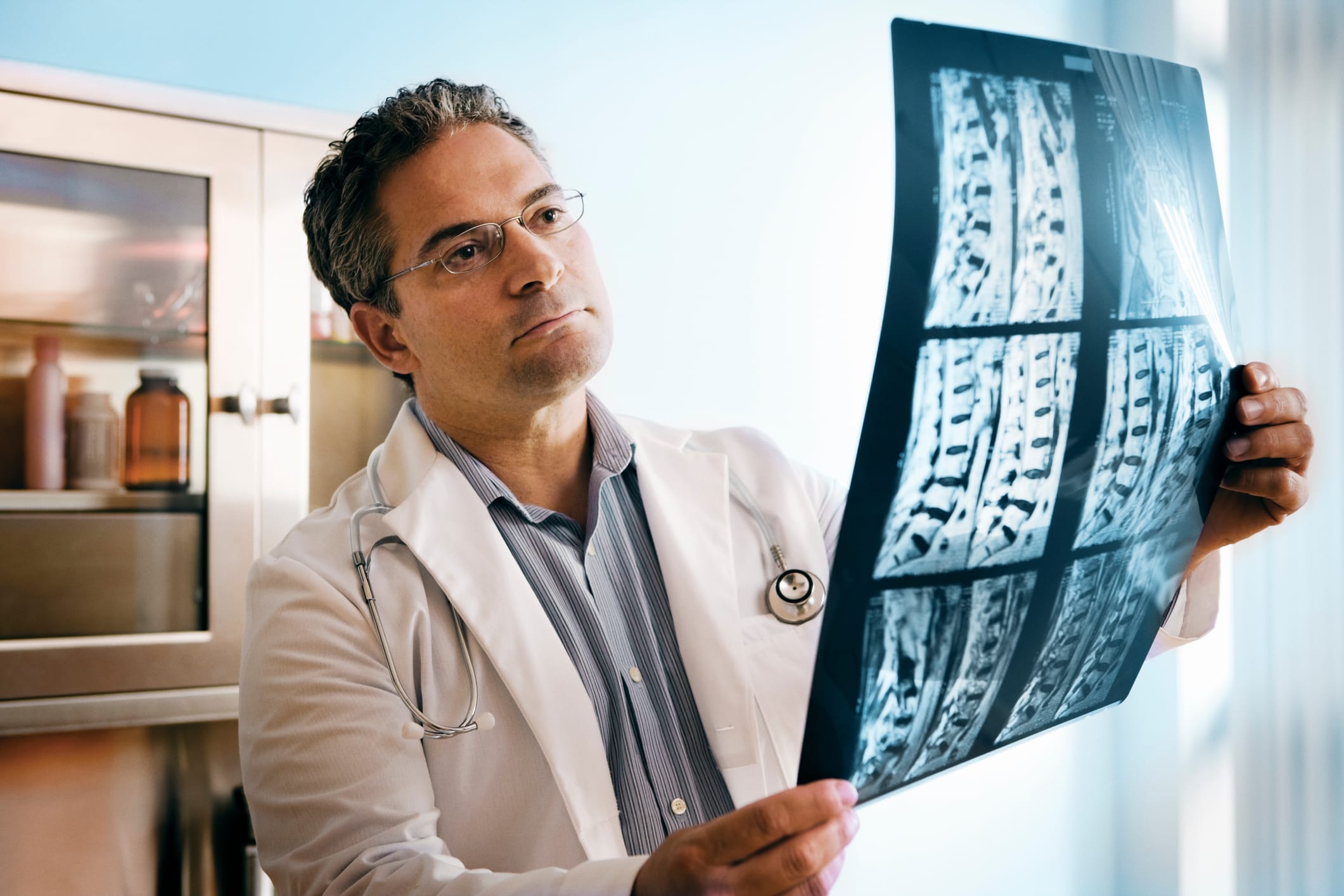 A doctor reviews MRI images of a damaged spine.