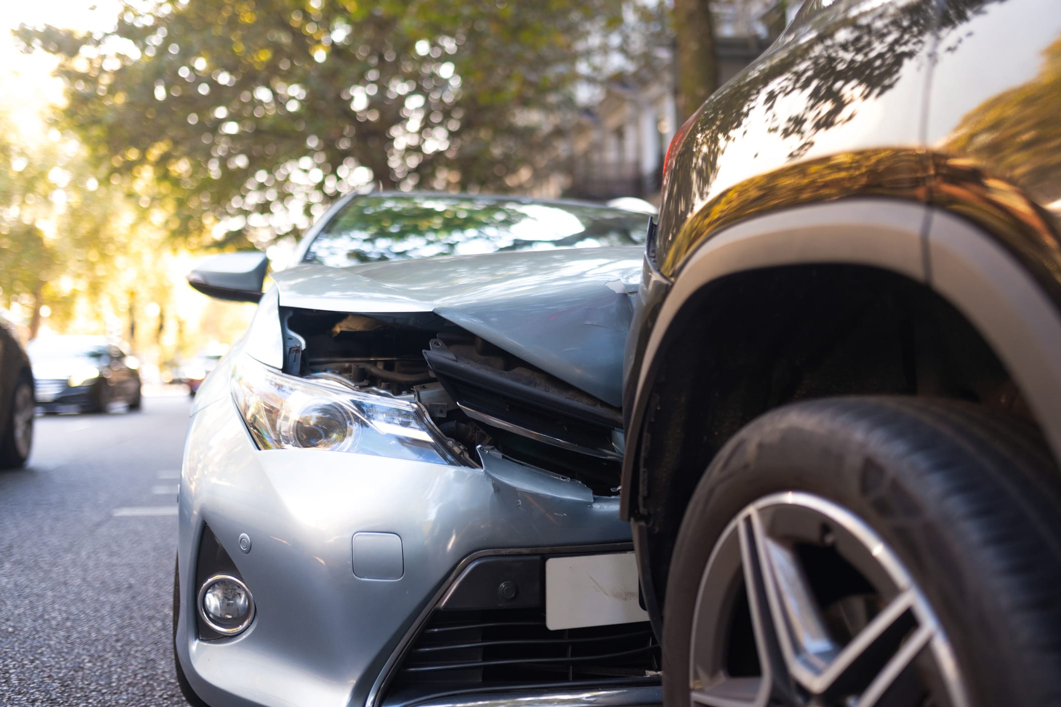 A close-up view of a head-on collision. The silver car in view has front-end damage.