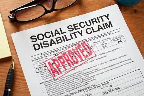Approved Social Security disability claim form on a desk with glasses and a pen.