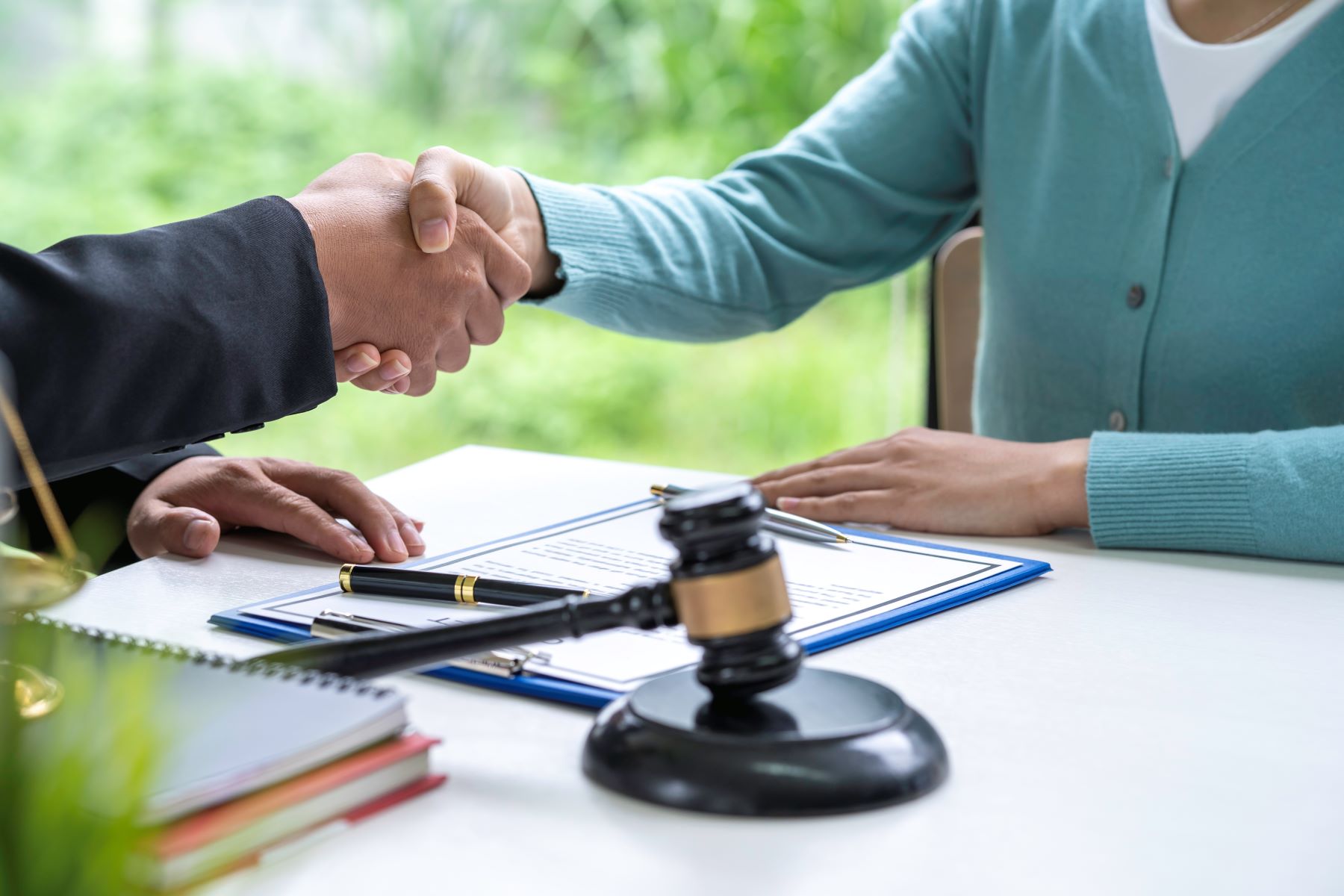 Closeup of attorney and client shaking hands during personal injury settlement process.