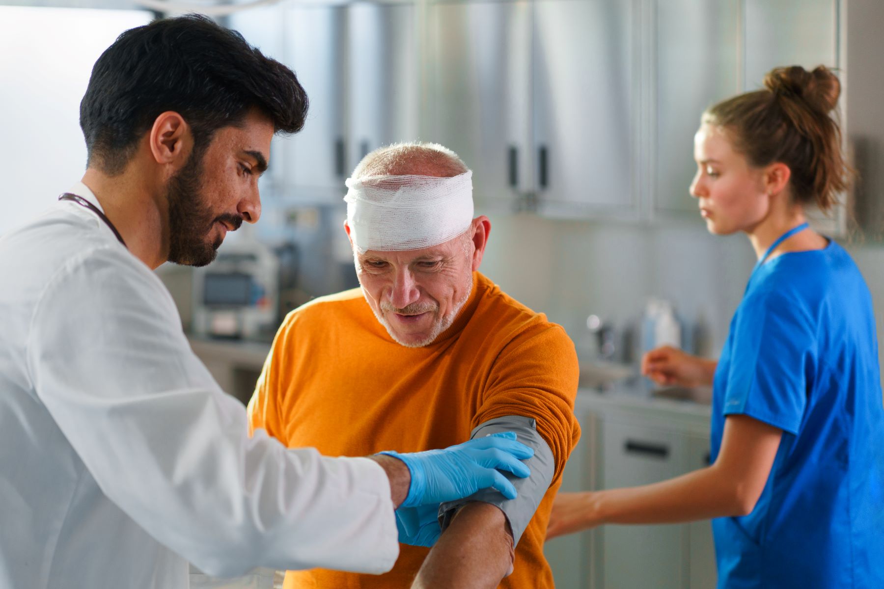 Older man with a head injury is treated by a doctor and nurse in Massachusetts after a car accident.
